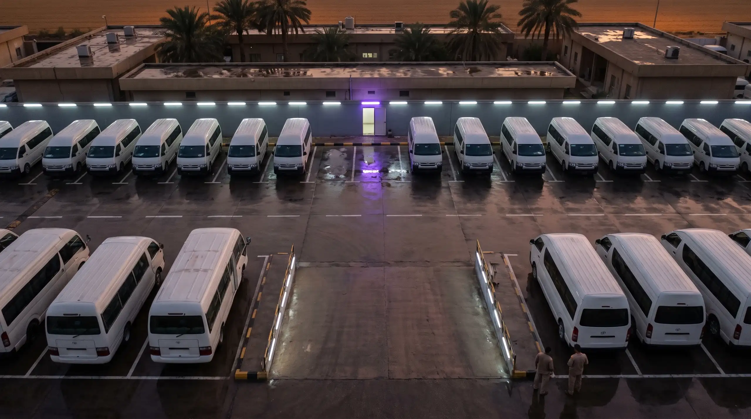 An elevated view over a lit depot with parked vans