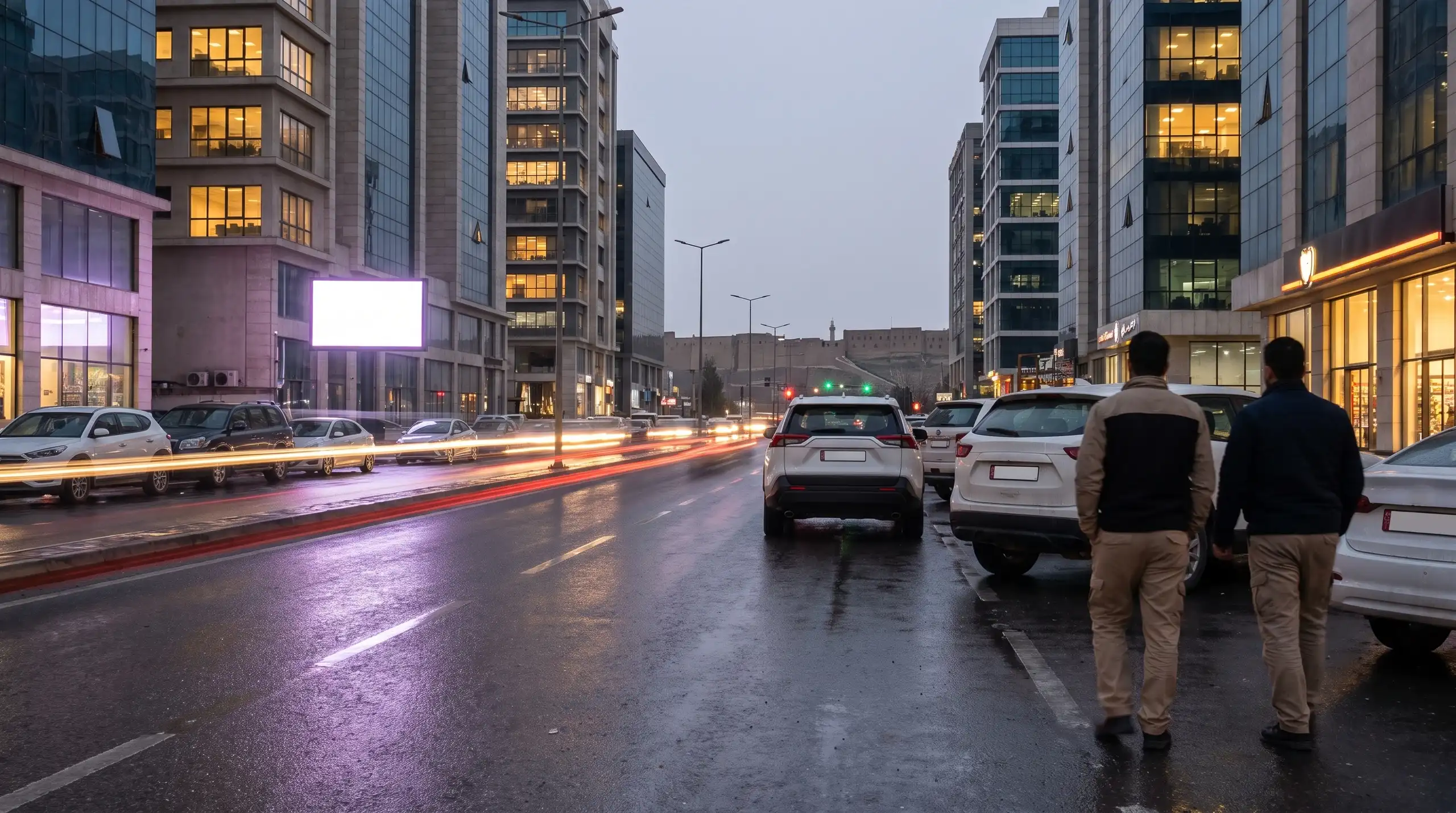Office towers above a wet boulevard at night