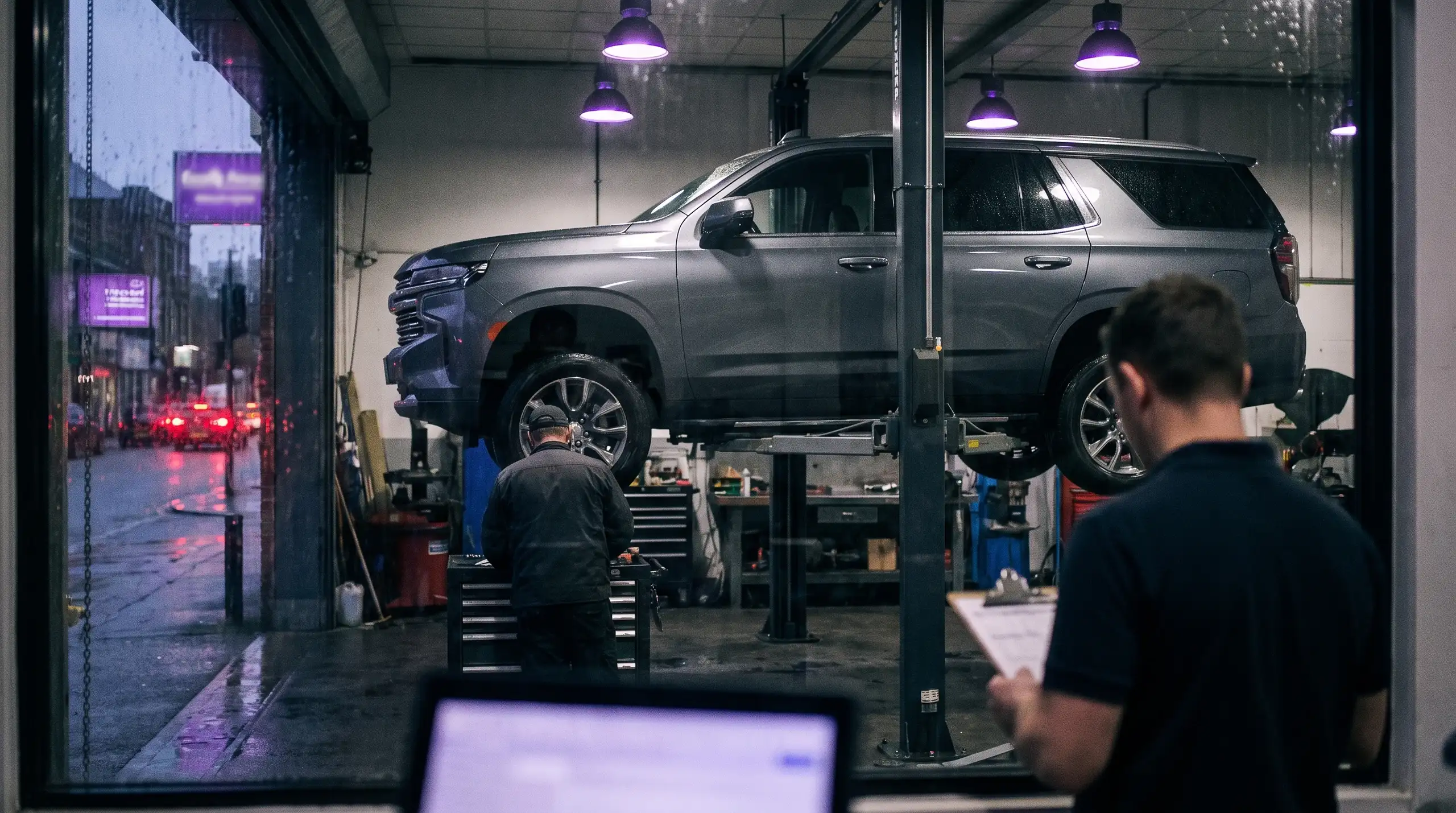 An SUV raised on a lift in a workshop at night