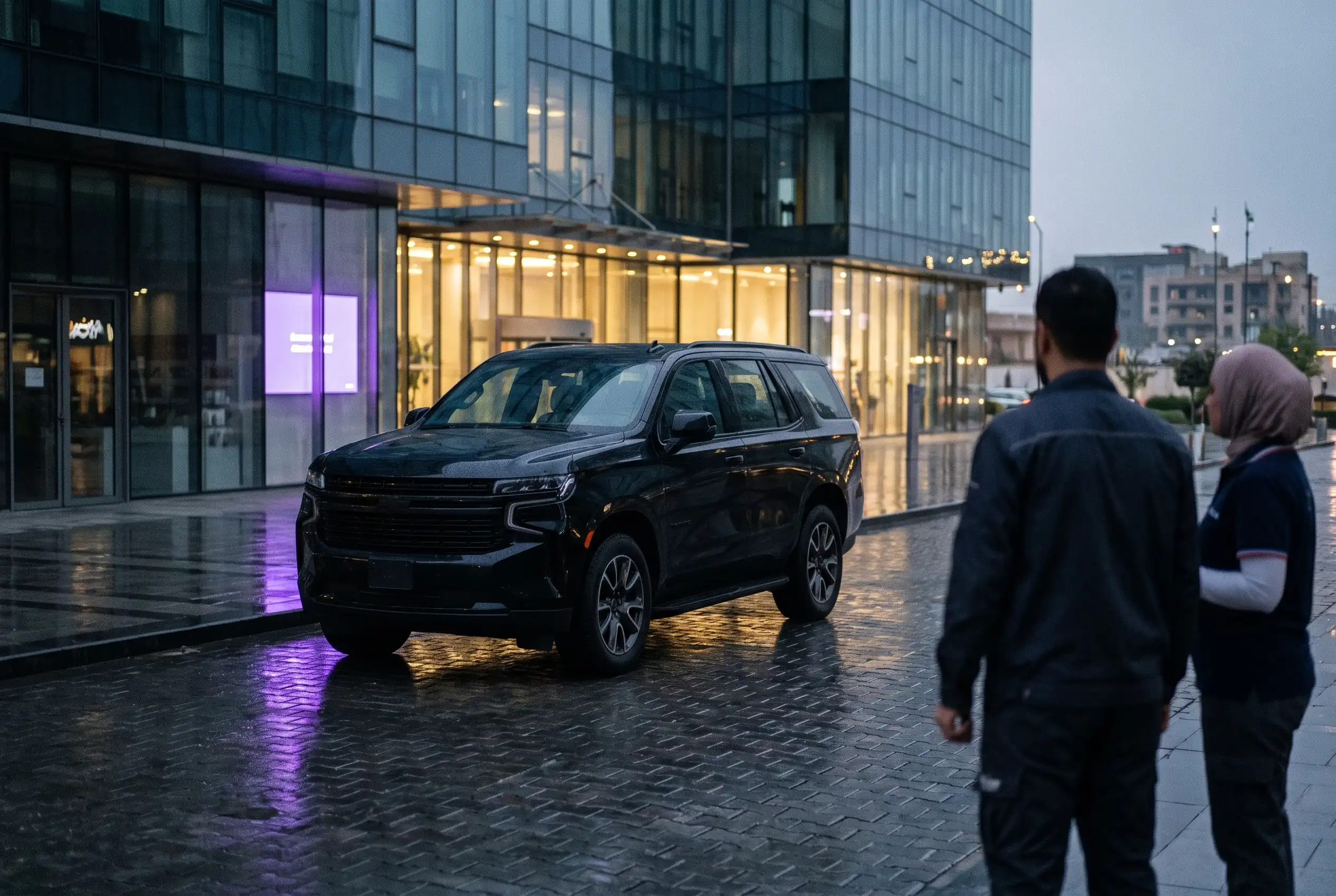 A dark SUV in front of an office facade at night